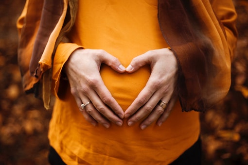 pregnant woman making a love heart with her hands